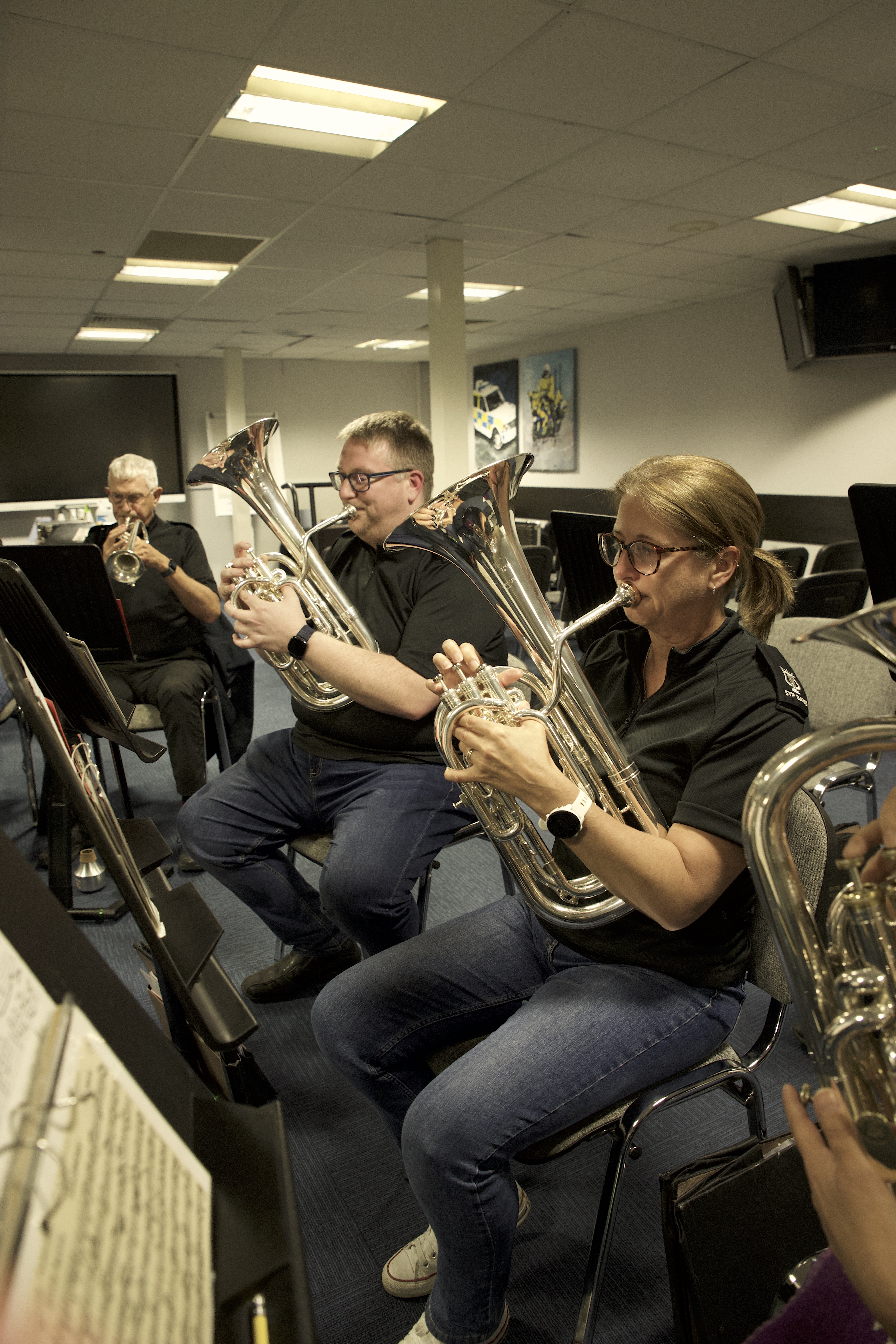 a rehearsal with south yorkshire police band volunteer musicians seated playing brass instruments 